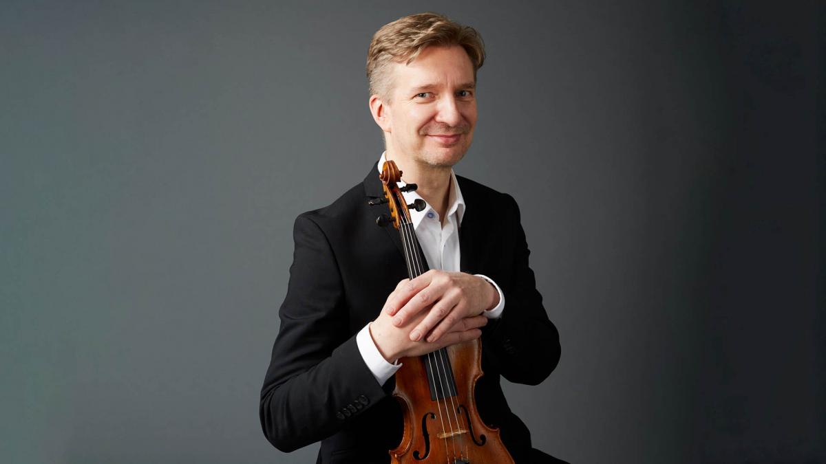 Teppo Ali-Mattila poseeraa viulun kanssa harmaata taustaa vasten