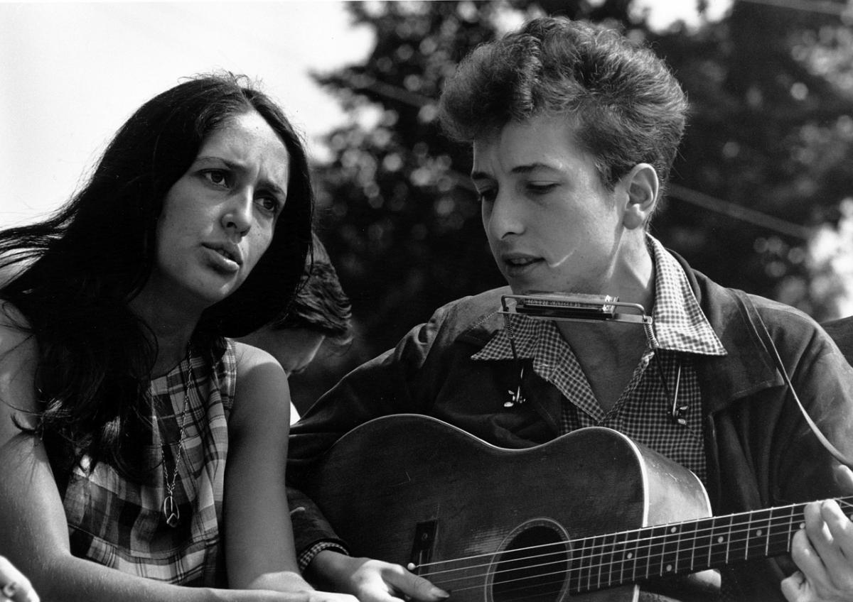 Bob Dylan soittaa kitaraa nainen vierellään.