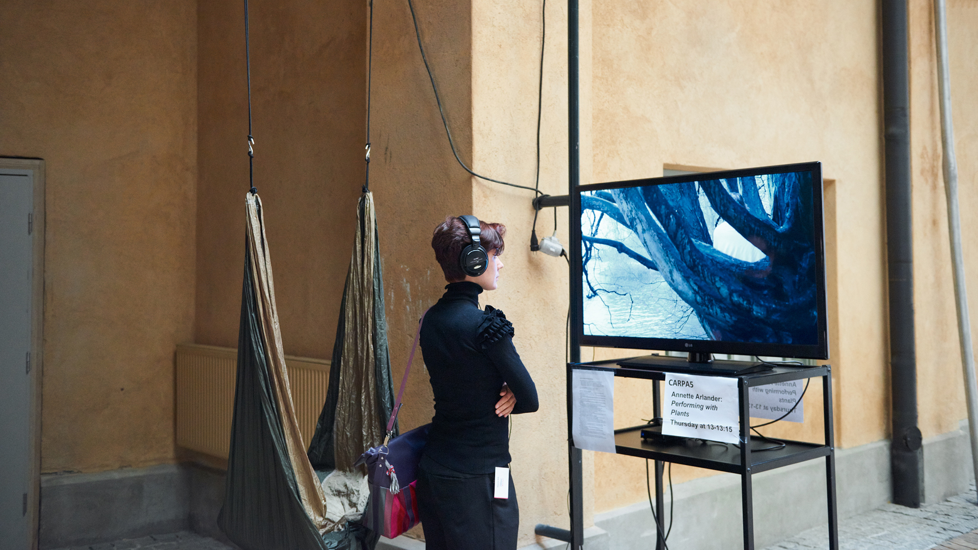 Person watching a video installation wearing a headset. Located in the Theatre Academy's premises.