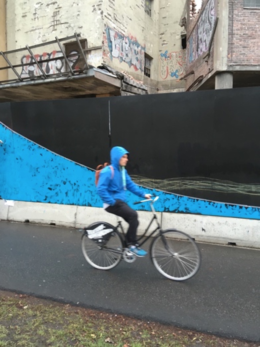 a person riding a bicycle in front of a balck and blue construction site fence