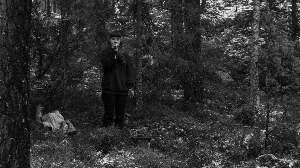 In the photo, Minerva Juolahti stands in a forest with a microphone and a speaker during the seison metsässä performance. Photo: Joona Mäkelä. 