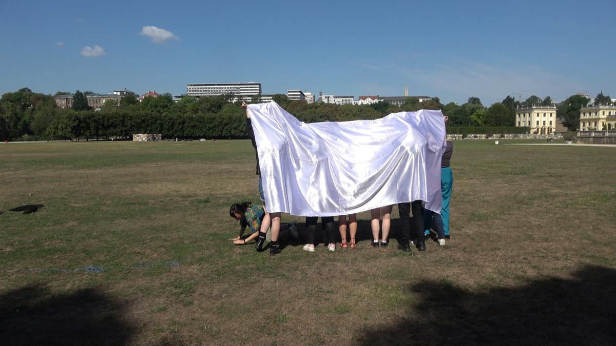 Group of people outside under a white sheet