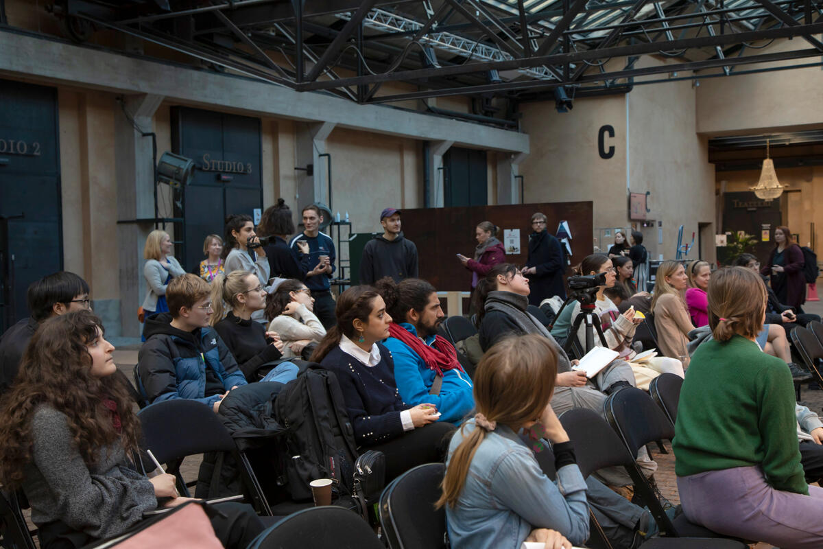 Audience of students sitting and following discussion on stage.