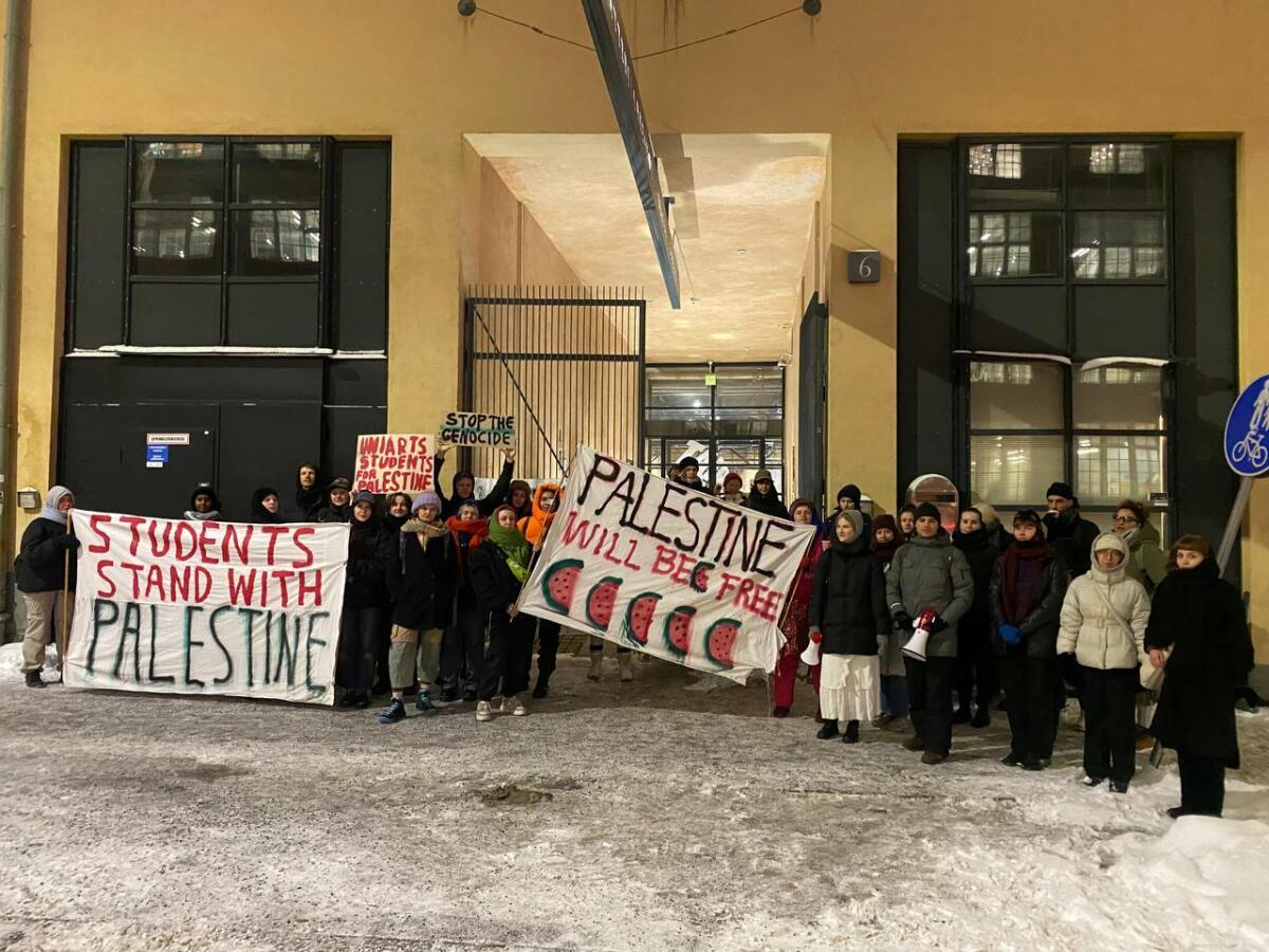 Students are leaving from the Sörnäinen campus to protest in solidarity with Palestine. There are about 40 people. It's winter and people wear warm clothes. The carry banners saying "Students stand with Palestine", "Palestine will be free", "Stop the genocide", and "Uniarts students for Palestine".